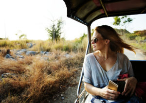 A woman sitting inside an open-air vehicle, in an exotic location, looks pensive yet excited about what lies ahead