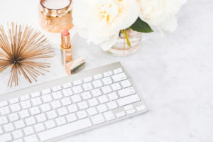 A feminine look of a keyboard, fresh white roses and other accessories, awaiting a client.