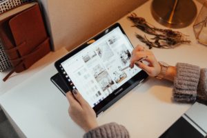 A woman works on her tablet, with a stylus writing pen. She circles a few things out of many, on the screen of her tablet.