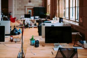 A bunch of desks with computers turned off, sit in an empty office space