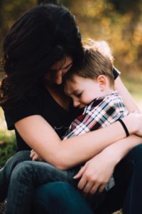 A mother is holding her toddler-aged son in her arms