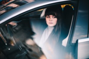 A woman sits in her car with a cold, mean look in her eyes...