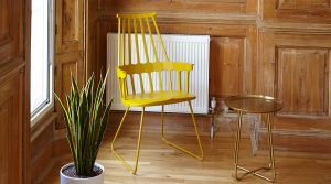 A re-purposed yellow chair looks quite unique next to a lovely plant sitting in front of a sunny window